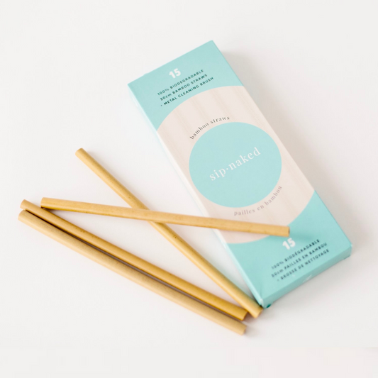 Four Sip Naked bamboo straws lying next to box. 